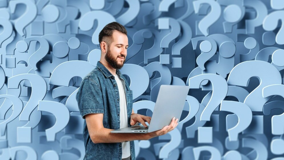 Pozadina od upitnika i muškarac na laptopu kako razmišlja