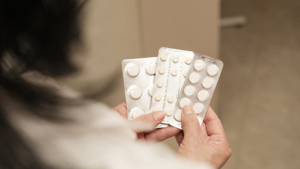 Žena srednjih godina koja drži nekoliko raznih tableta