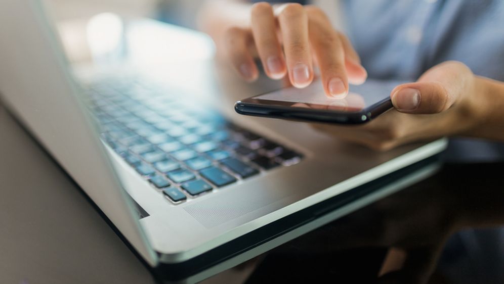 Žena koristi mobitel i laptop, ilustracija