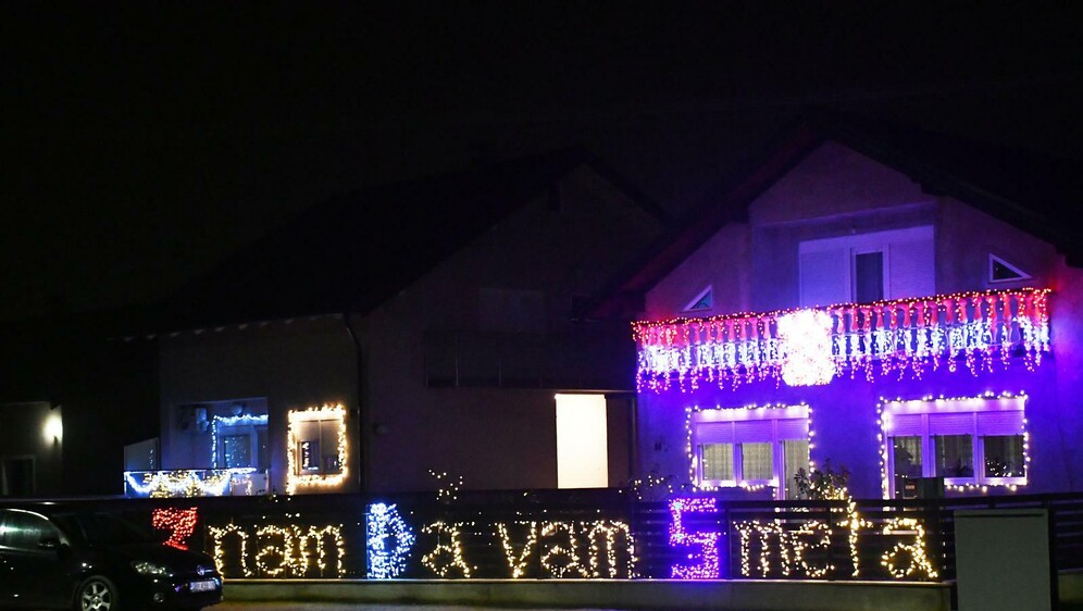 Kuća ukrašena tisućama lampica i osvijetljenom ogradom s natpisom