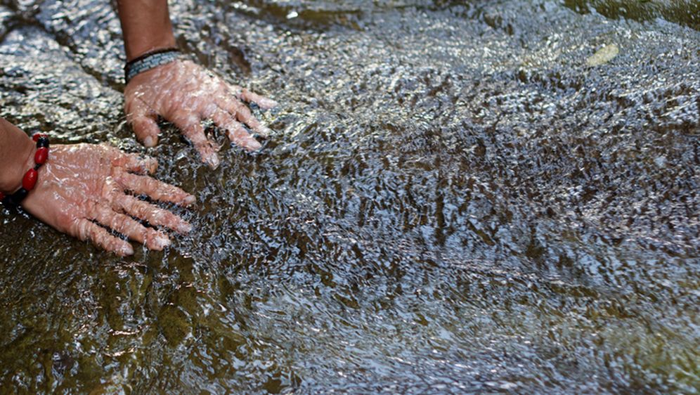 Žena s dlonovima uronjenim u rijeku