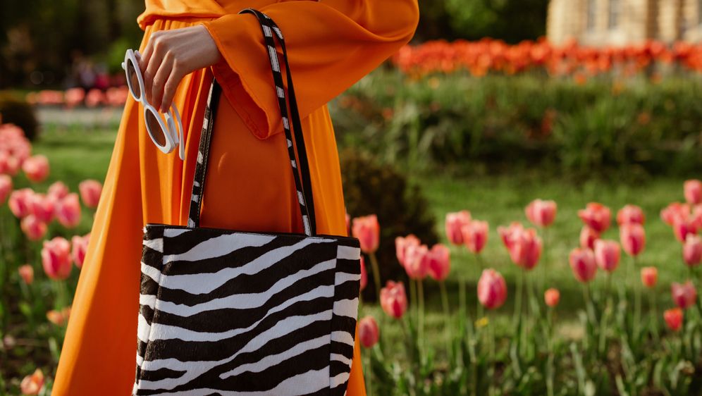 Žena u narančastom outfitu i s torbom sa zebrastim uzorkom
