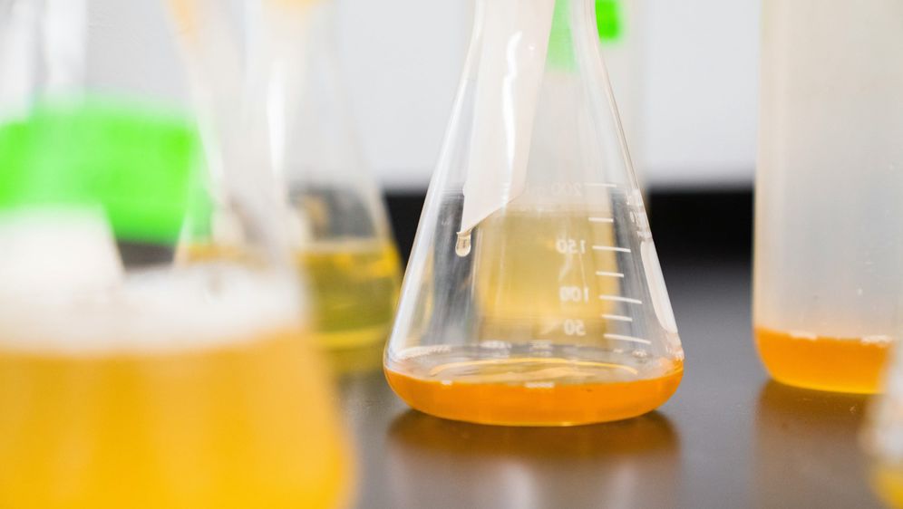 erlenmeyerove tikvice posložena na stolu pune narančaste tekućine u laboratoriju
