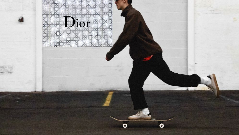 mladić koji vozi skateboard kraj natpisa modnog brenda dior
