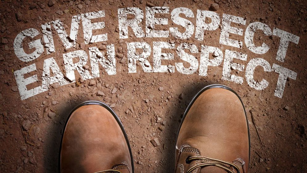 čizme i natpis u zemlji na kojem piše give respect earn respect