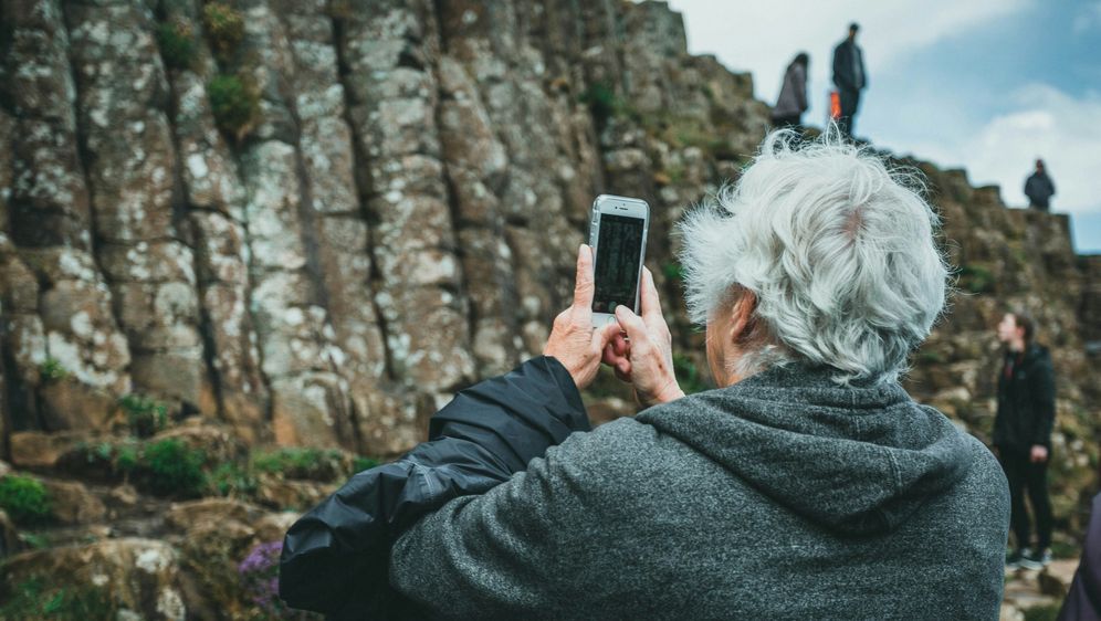 stariji sjedi muškarac kako na izletu u prirodi fotografira krajolik