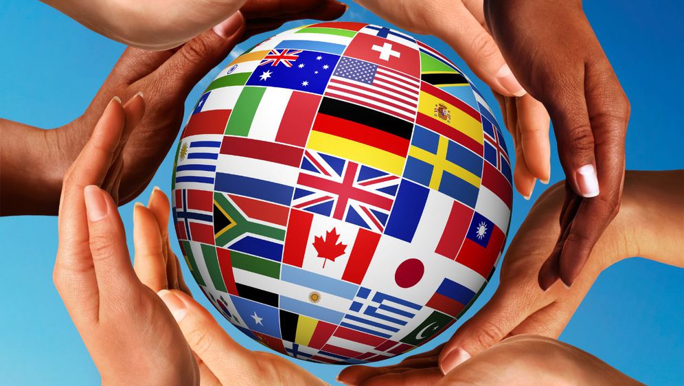 ruke koje okružuju globus na kojem su zastave nekih zemalja svijeta