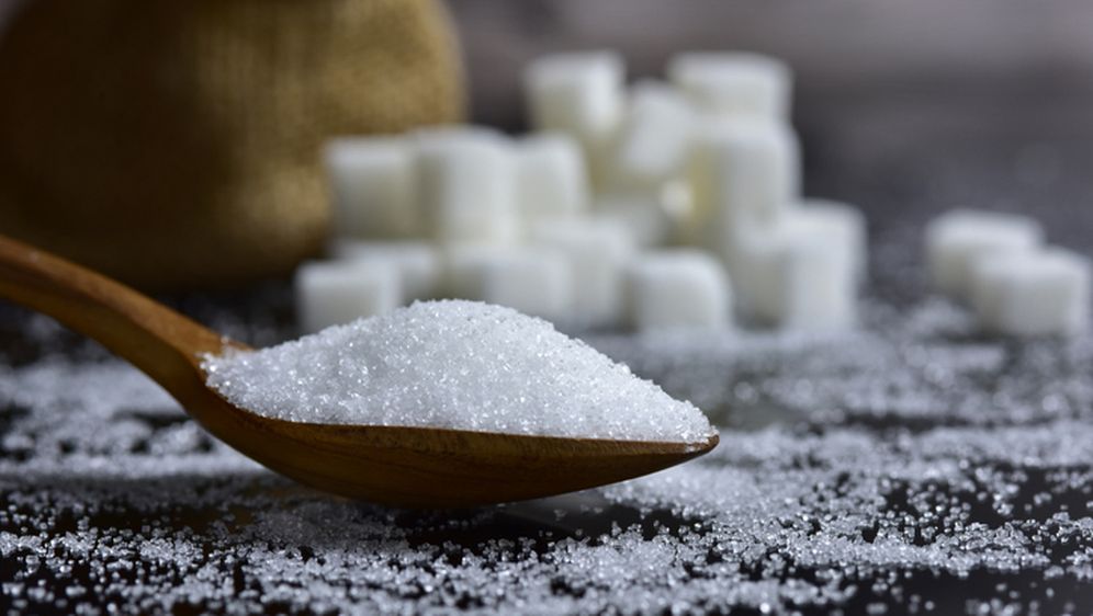 Žlica šećera i šećer u pozadini
