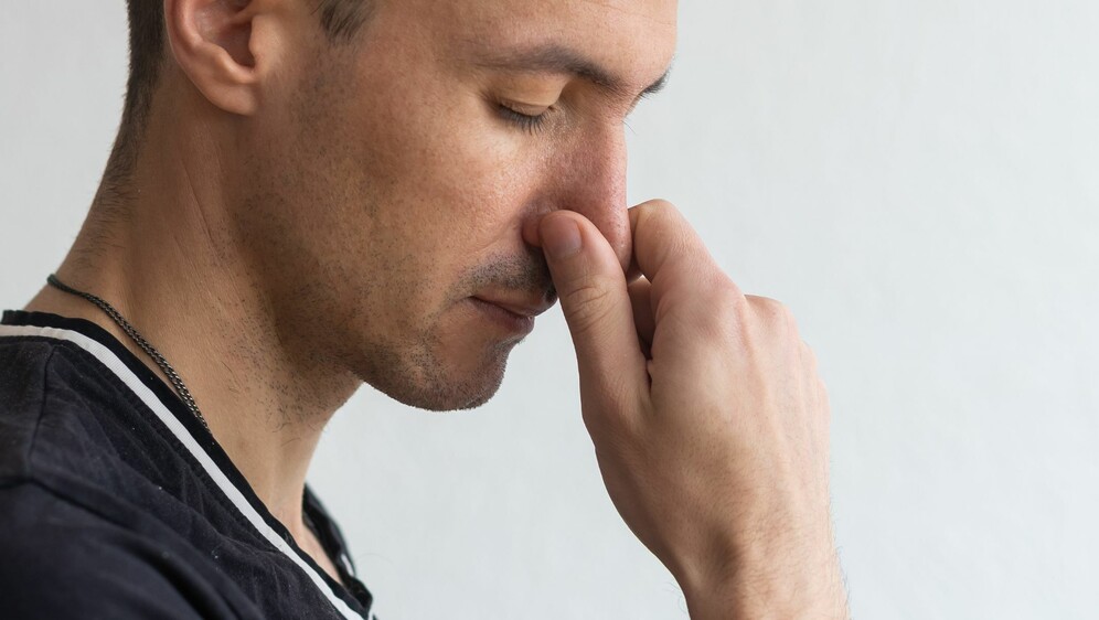 Muškarac koji se drži za nos