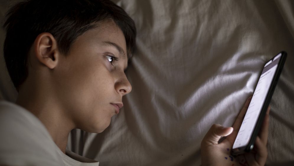 Dječak surfa na mobitelu u krevetu, ilustracija