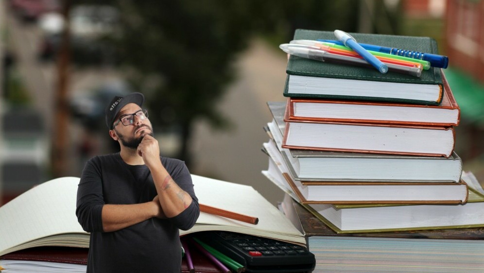 Razne knjige i pomagala u učenju uz muškarca koji razmišlja