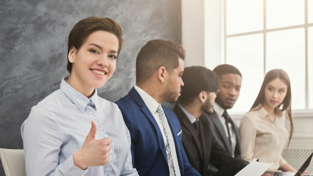 Kandidati za posao koji čekaju razgovor i žena s podignutim palcem