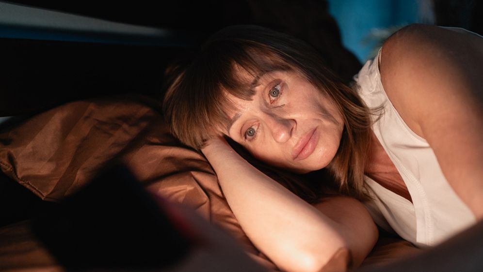 Žena gleda u mobitel u krevetu, ilustracija