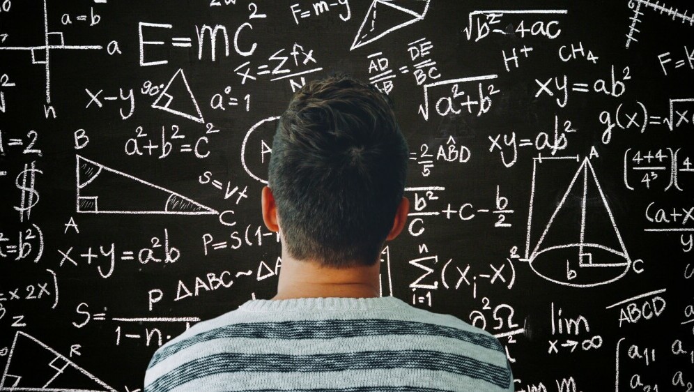 Muškarac kako razmišlja ispred ploče s matematičkim formulama