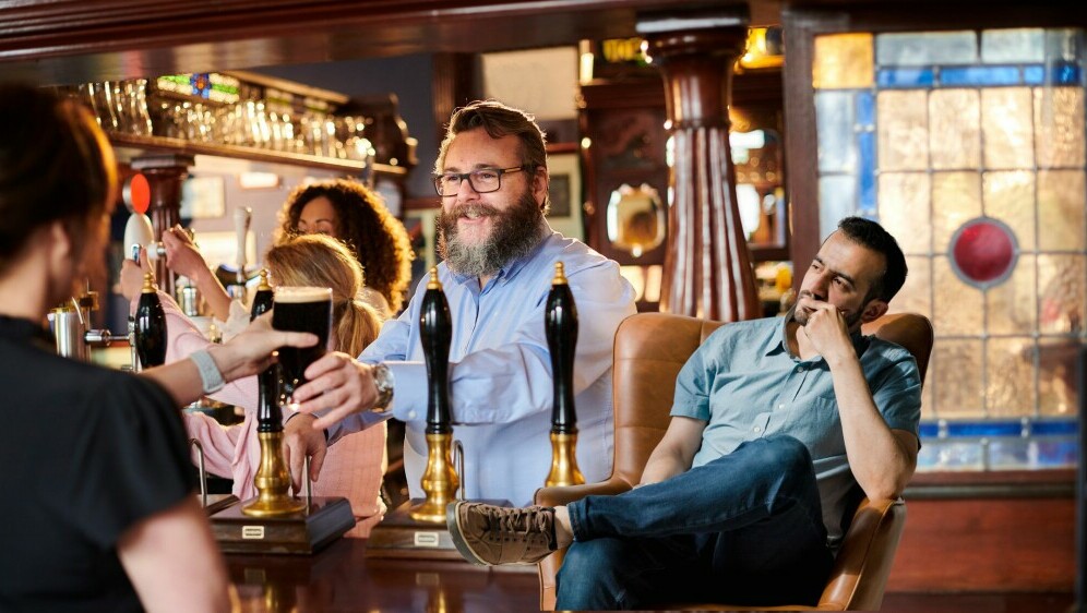 Konobara u Pubu kako toči piće i muškarac koji razmišlja